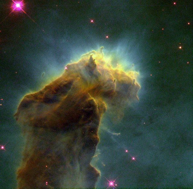 This eerie, dark structure, resembling an imaginary sea serpent's head, is a column of cool molecular hydrogen gas (two atoms of hydrogen in each molecule) and dust that is an incubator for new stars. The stars are embedded inside finger-like protrusions extending from the top of the nebula. Each "fingertip" is somewhat larger than our own solar system. The pillar is slowly eroding away by the ultraviolet light from nearby hot stars, a process called "photoevaporation." As it does, small globules of especially dense gas buried within the cloud is uncovered. These globules have been dubbed "EGGs" -- an acronym for "Evaporating Gaseous Globules." The shadows of the EGGs protect gas behind them, resulting in the finger-like structures at the top of the cloud. Forming inside at least some of the EGGs are embryonic stars -- stars that abruptly stop growing when the EGGs are uncovered and they are separated from the larger reservoir of gas from which they were drawing mass. Eventually the stars emerge, as the EGGs themselves succumb to photoevaporation. The stellar EGGS are found, appropriately enough, in the "Eagle Nebula" (also called M16 -- the 16th object in Charles Messier's 18th century catalog of "fuzzy" permanent objects in the sky), a nearby star-forming region 7,000 light-years away in the constellation Serpens. The picture was taken on April 1, 1995 with the Hubble Space Telescope Wide Field and Planetary Camera 2. The color image is constructed from three separate images taken in the light of emission from different types of atoms. Red shows emission from singly-ionized sulfur atoms. Green shows emission from hydrogen. Blue shows light emitted by doubly-ionized oxygen atoms. 